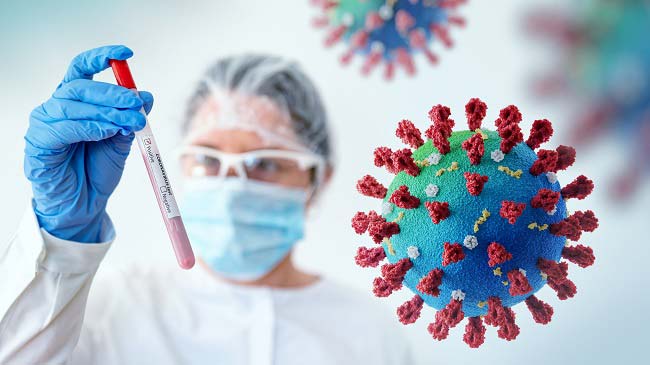 A female scientist wearing a hairnet, mask, eyewear and a blue glove is holding a red test tube