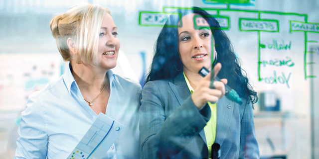 Two business women of differing ethnicities working together in the office