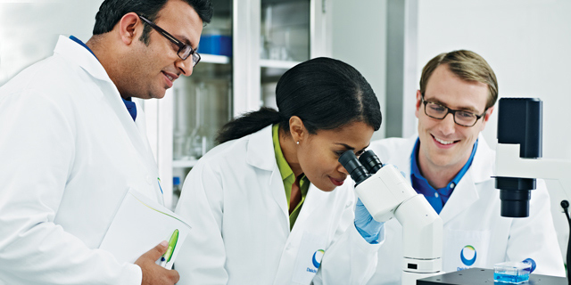 3 scientists working in a laboratory. 2 men and 1 woman of differing ethnicities