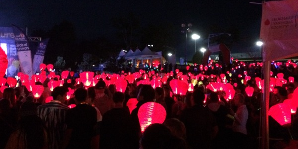 A large crowd gathering at night holding Gus Manz lanterns