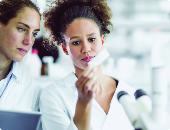 2 women in lab coats looking at a sample